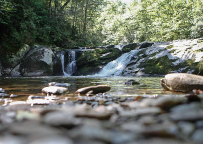 A serene waterfall cascades over moss-covered rocks