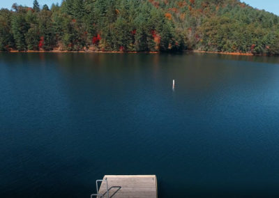 A tranquil lake scene with a wooden dock, surrounded by trees