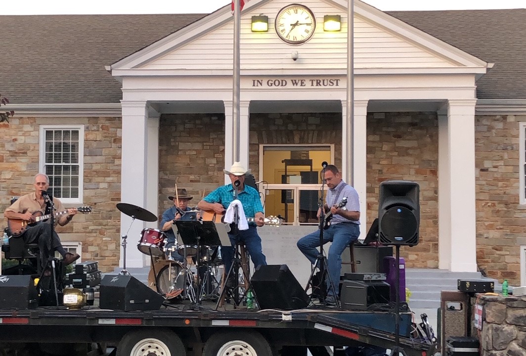 A lively band performs on a trailer in front of a stone building