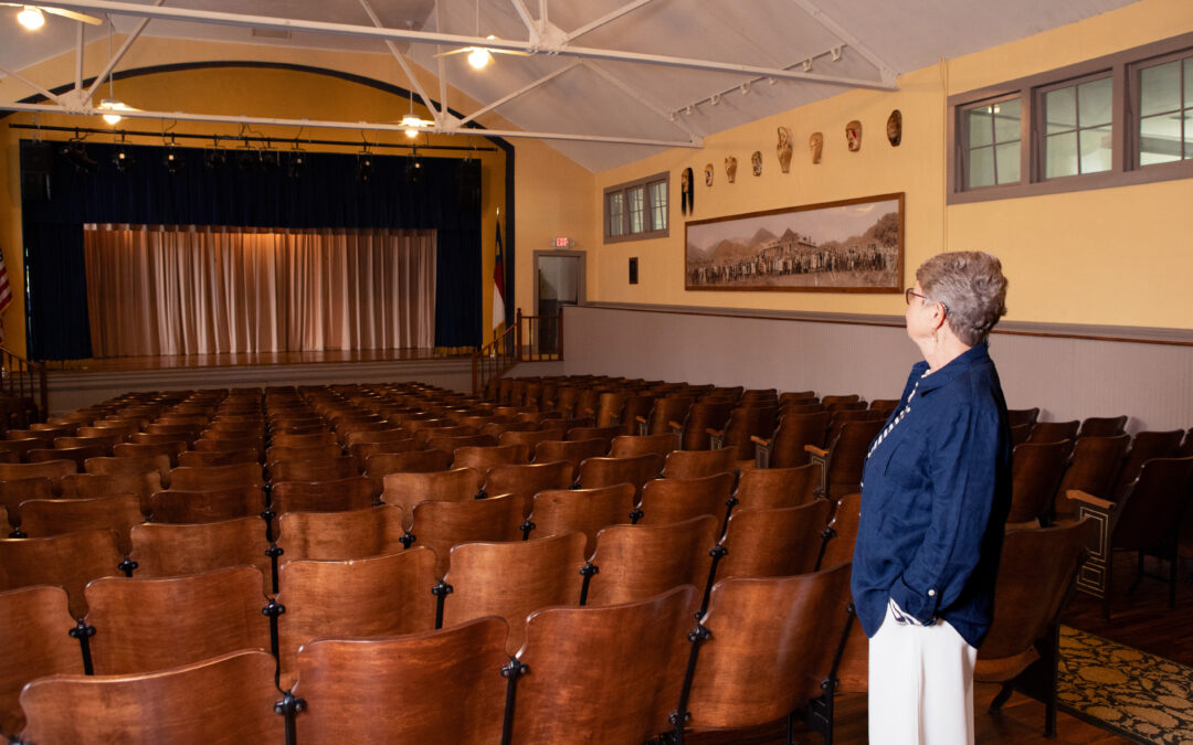 First Director of Stecoah, Lynn Shields looking toward the stage of the auditorium with rows of wooden seats in front of her
