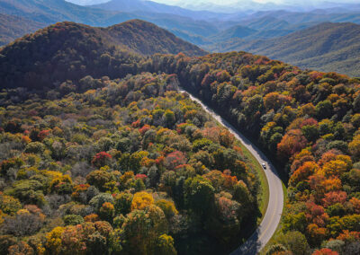 A winding road cuts through vibrant autumn forests