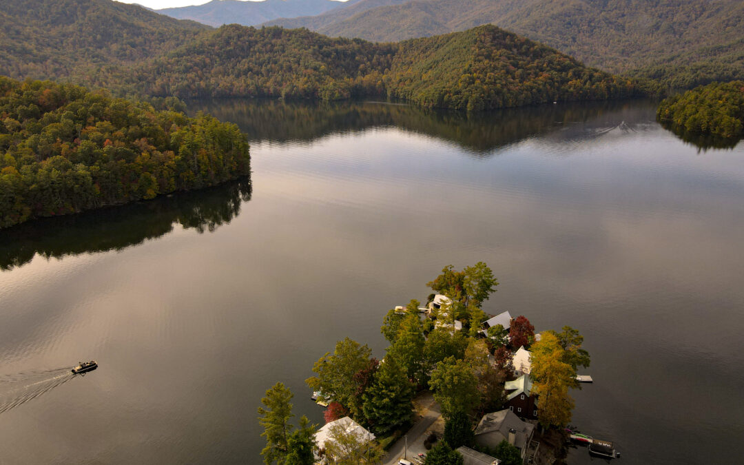 Lake Santeetlah in Fall with Boat in motion and a few houses on the shore.